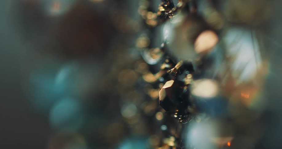 A round white jewel dangles from a reflective gold chain