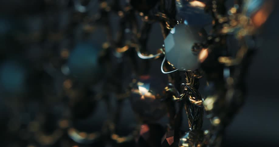 A jewelry object hanging from a reflective iron chain