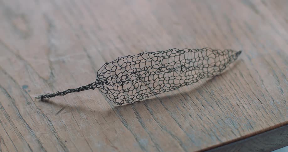A leaf decoration made of wire resting over a table
