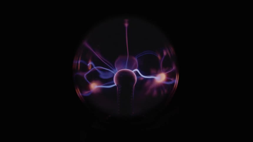 A plasma ball tesla coil lights up a dark room