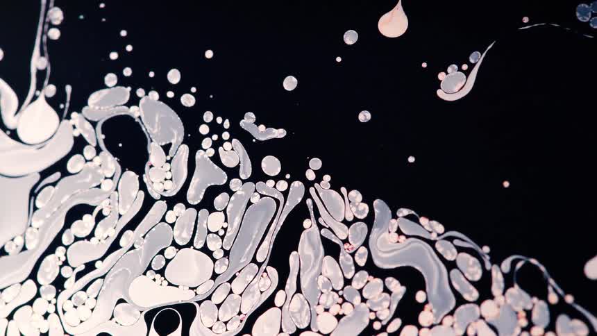 Pale pink and gray shapes flow across blackness liquid to cluster together