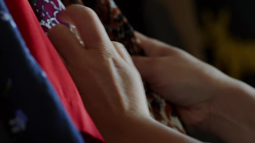 Hands of a woman selecting clothes from the closet