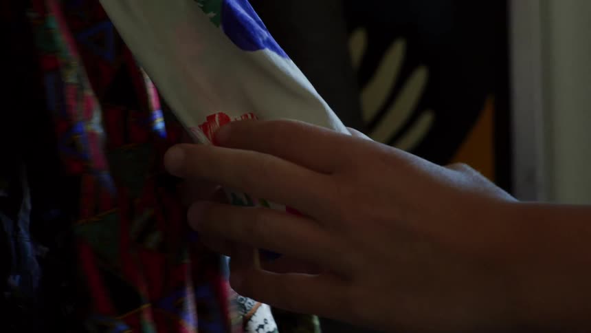 A person slowly strokes the material while holding a blouse