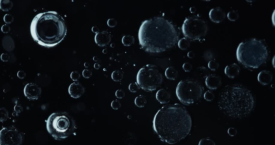 Several bubbles of different shapes and sizes in a black liquid