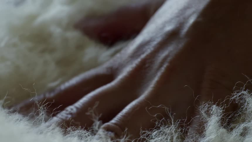 A human hand squeezing a fabric with several fibers