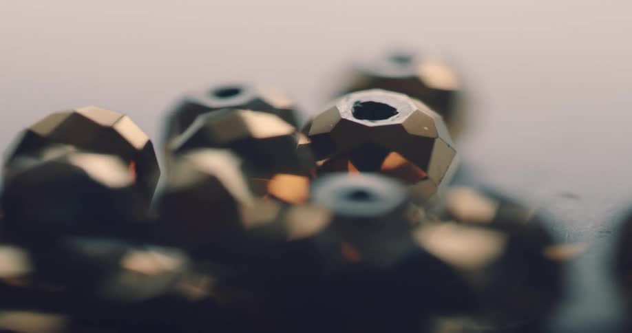 Shiny flat edged dimensional beads sit on a table as light shines upon them