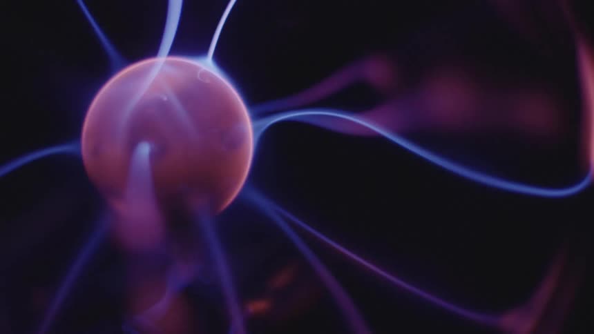 Glowing blue electrical appendages stretch and move from a pink sphere as it turns in the darkness