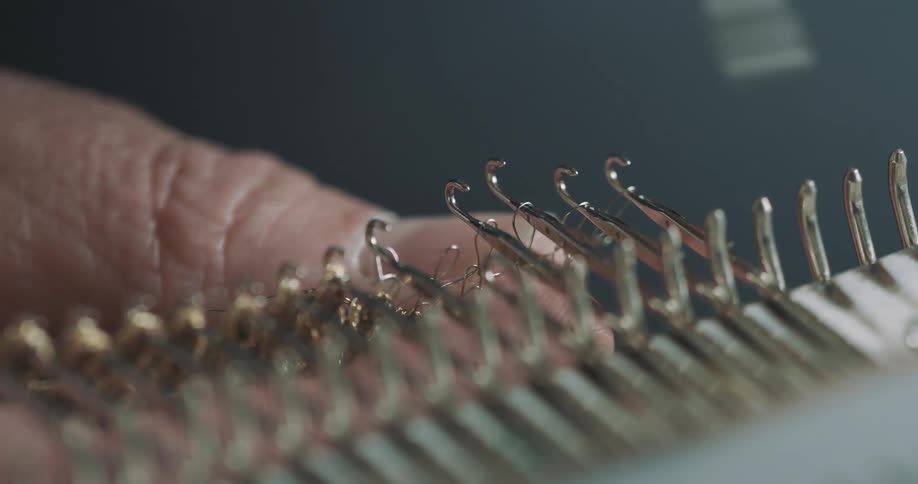 A person uses a needle to attach wires to a crochet machine