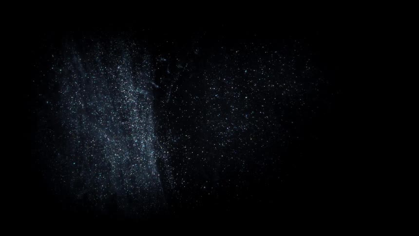 Glowing pinpoints of light move and fall in the darkness