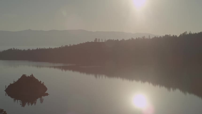 The sun is setting on this lake on a cloudy day