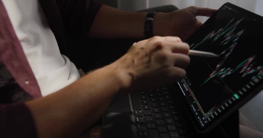 Man looking at stock exchange graphs on a laptop