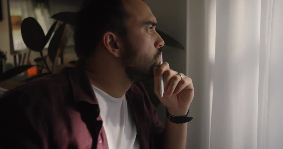 A man on his couch working on his laptop thinks to himself