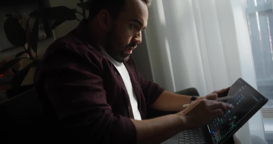 The man is working on his laptop and is frantically tapping on the screen and talking to himself