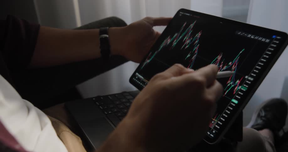 Man follows a stock investment chart on a laptop