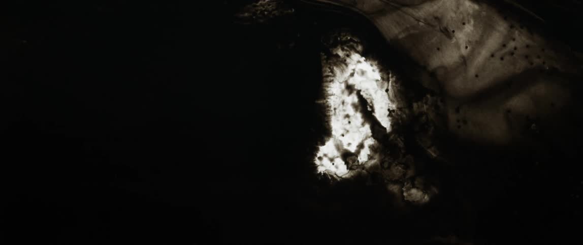 Dark black ink flows inwards bloating a source of light