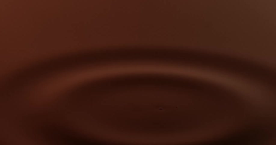 Droplet falling on maroon water and causing a ripple