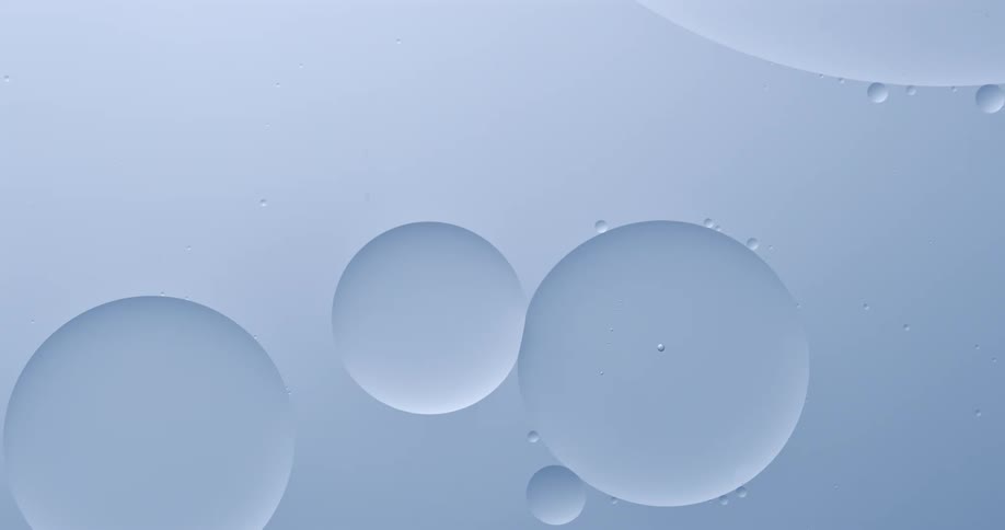 Large bubbles floating on pale blue liquid merge