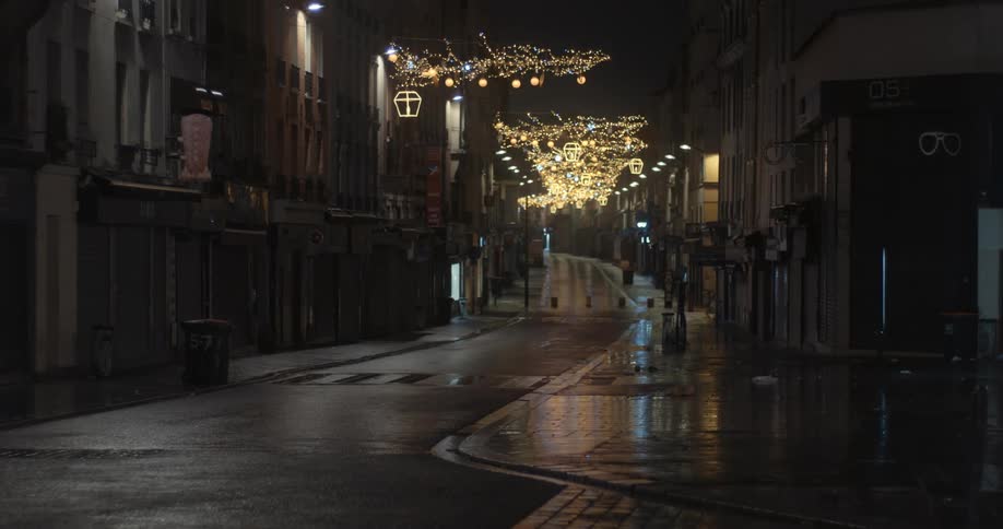 Puddles shine under street lights on an empty city street