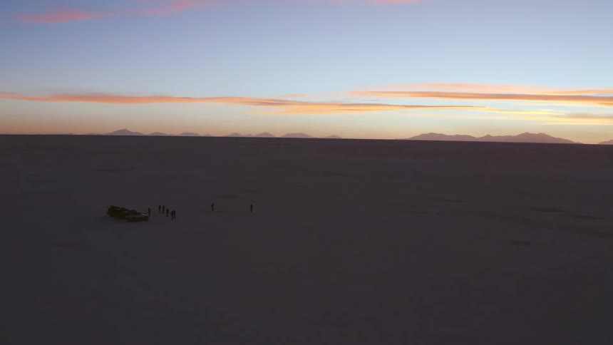 Group of people stand near vehicles at dusk