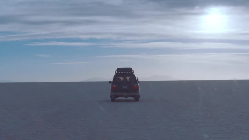 A car with luggage on top of it moving at dawn