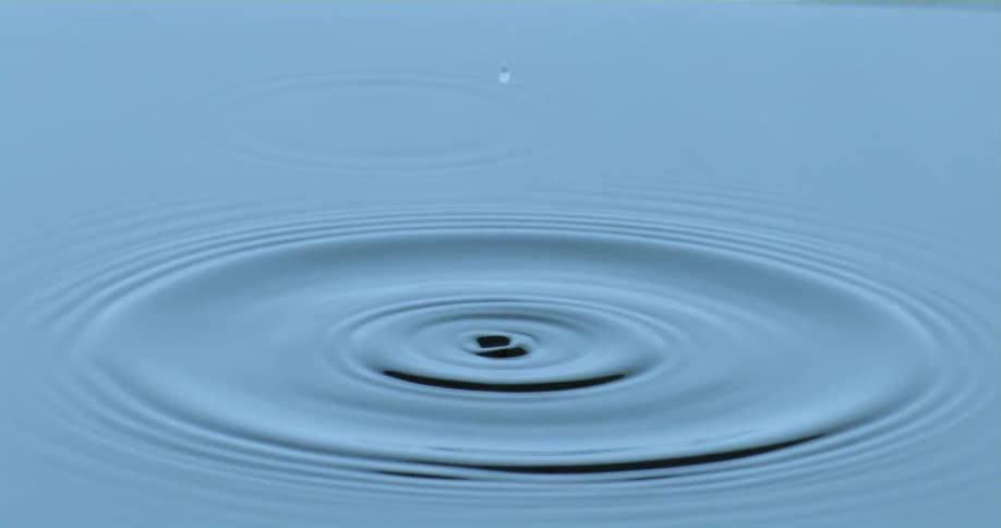 A drop of water falling into a pool of water causing ripples