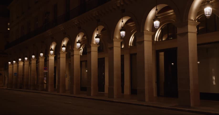 A tall building with a taste of old architecture full of arches and lanterns along the side and there are doors to enter the building