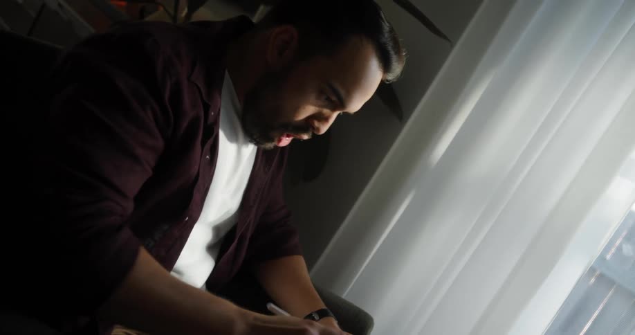 Man sitting on an armchair in a living room is suddenly scared by assets price graph displayed on his laptop screen