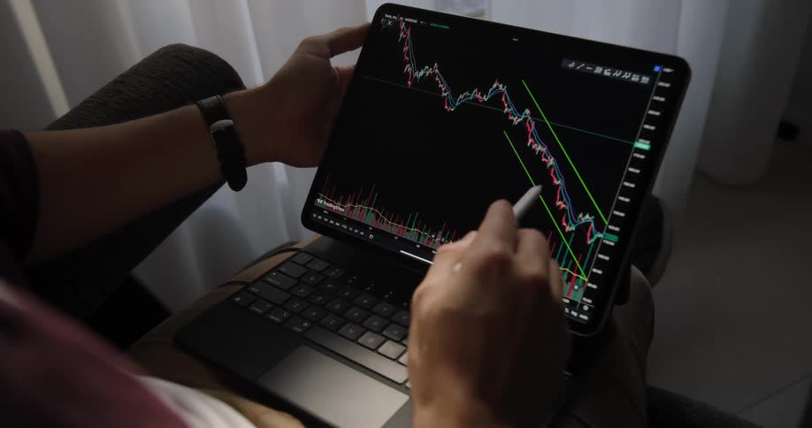 A man is sitting in a chair with a computer in his lap as he moves a stylus across the screen