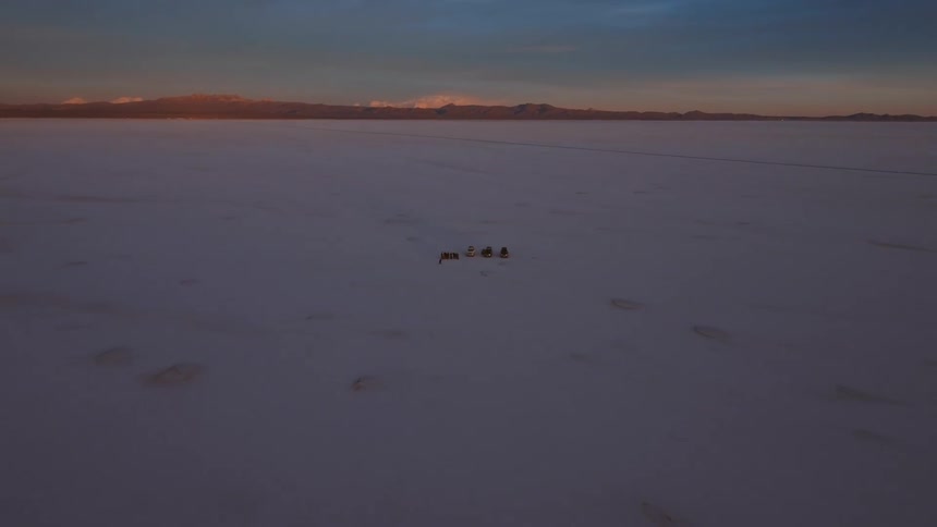 Peole around vehicles parked in the desert next to a mountain range