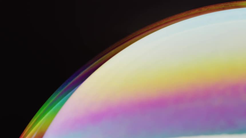 A sphere covered in soft pastel stripes and a fluorescent atmosphere moves in the darkness