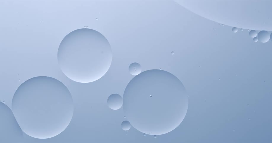 Orbs are floating in a liquid substance as two spheres touch and merge into one