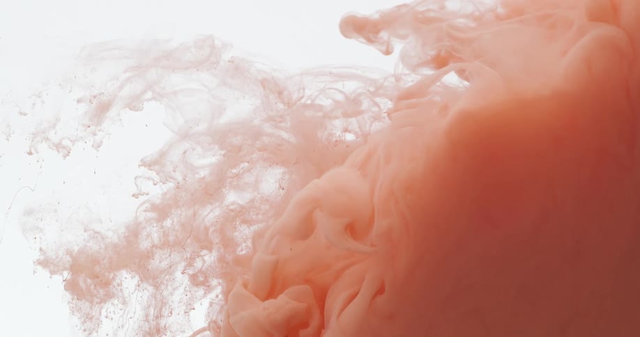 Cloud of bright liquid orange ink floats on a white background