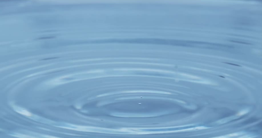 A closeup shot of a drop of water falling into water creating ripples