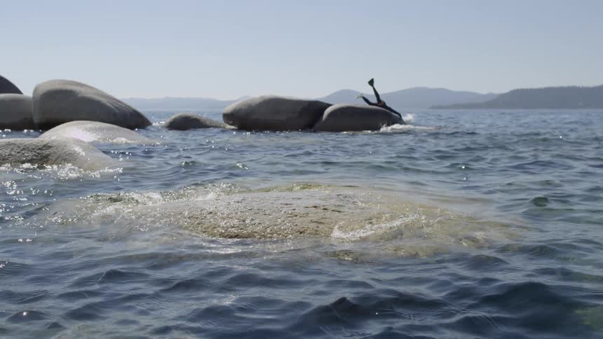 A person jumps off large rocks diving in the water