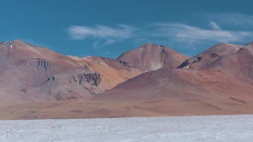 Landscape of hills and slopes next to salty plains on a salt desert during day time