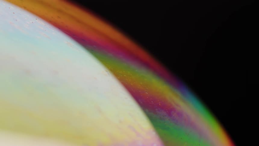 Colorful reflections on the surface of a soap bubble against a dark background