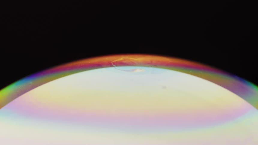 Band of rainbow colors swirls on edge of glowing sphere against a dark background