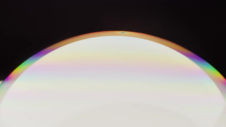 Soft fluorescent stripes move around the edges of a glowing white sphere in a black environment