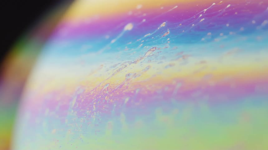 Spherical object orbiting in an abstract rainbow formation on a black background