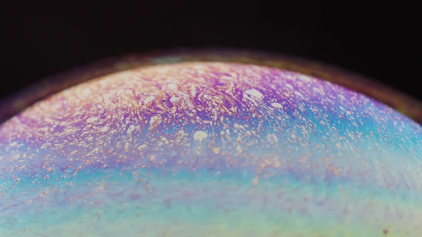 Multicolored mixture swirls under the filmy surface of a bubble
