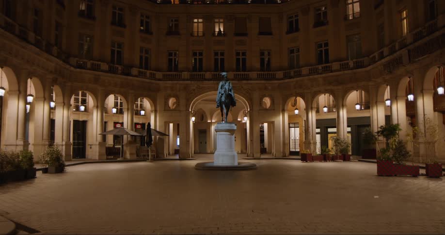 A statue in the middle of a building build in a circular shape at night with lights shinning