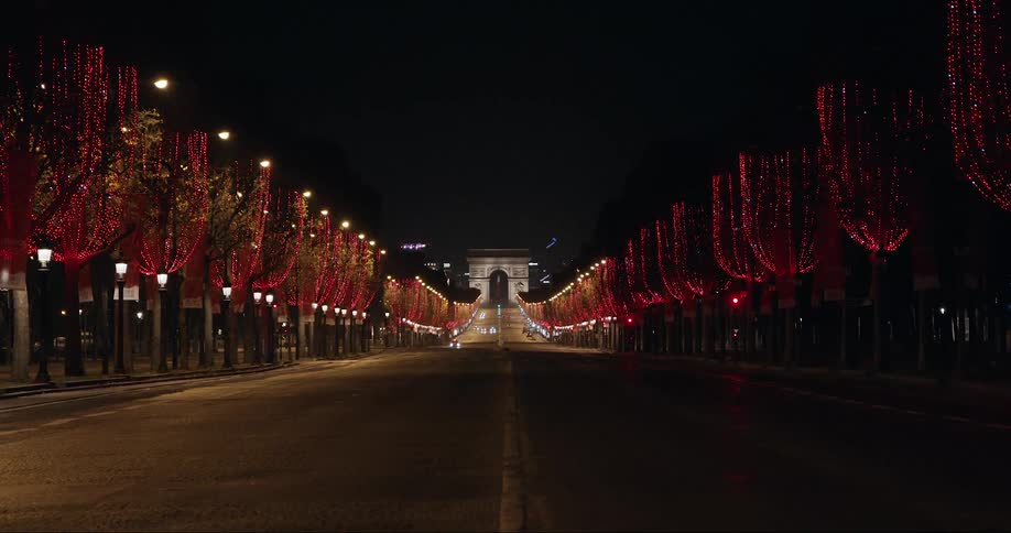 A bridge at night is lit up by glittering red lights on trees lining the road