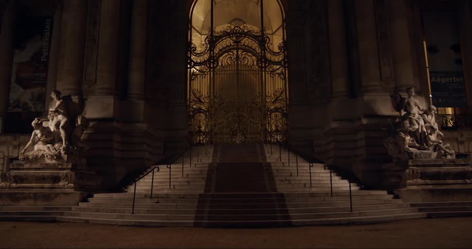 An entrance to a building with statues outside and a staircase with handrails