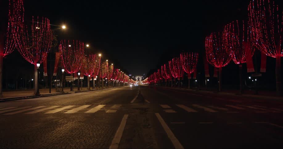 Red christmas lights decorate the trees on the city streets