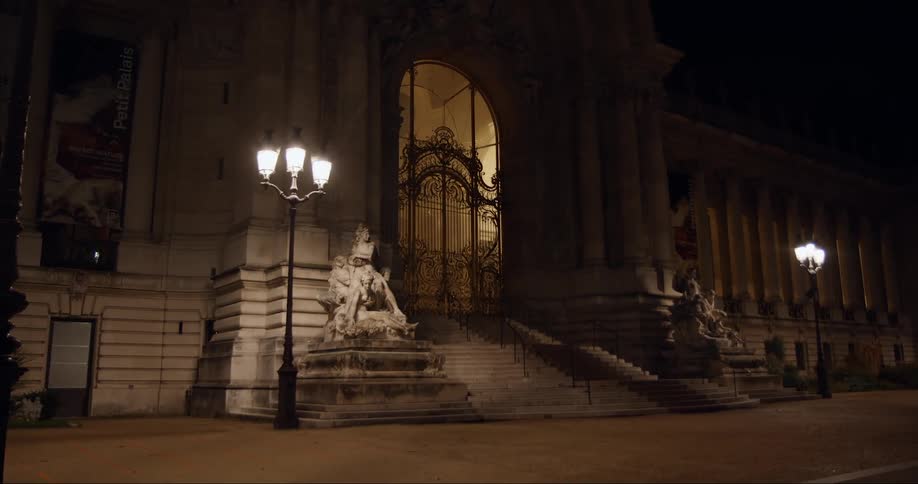 Sculptures under street lights at the entrance of a classical building