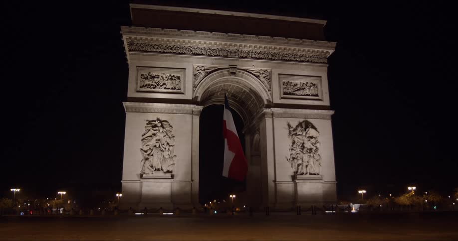 Flag flutters slightly under center of the arc de triomphe at night