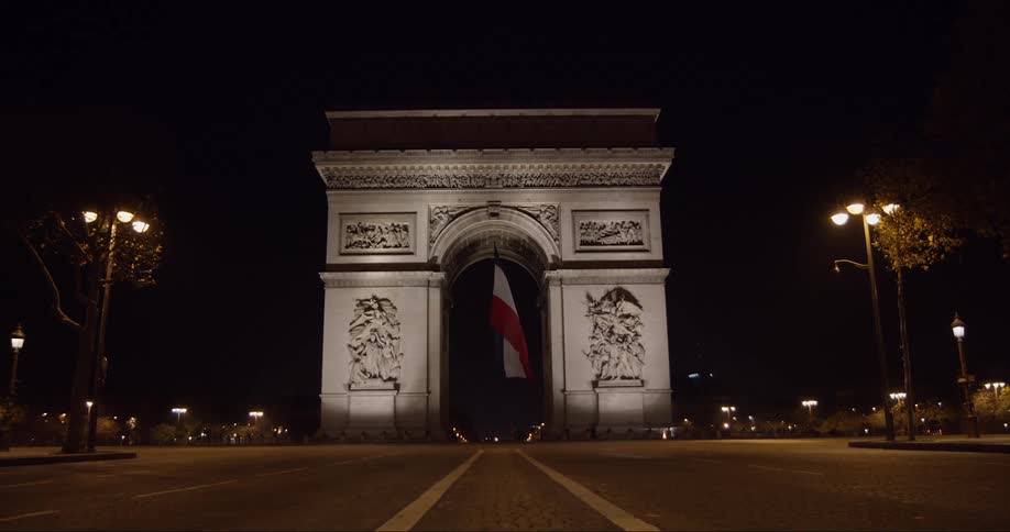 A monument on the road with a france flag at night