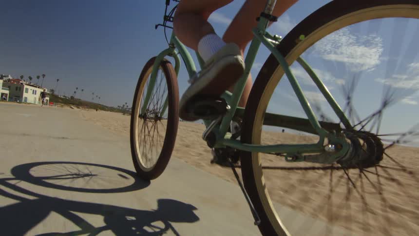 A woman is riding her bicycle on the beach