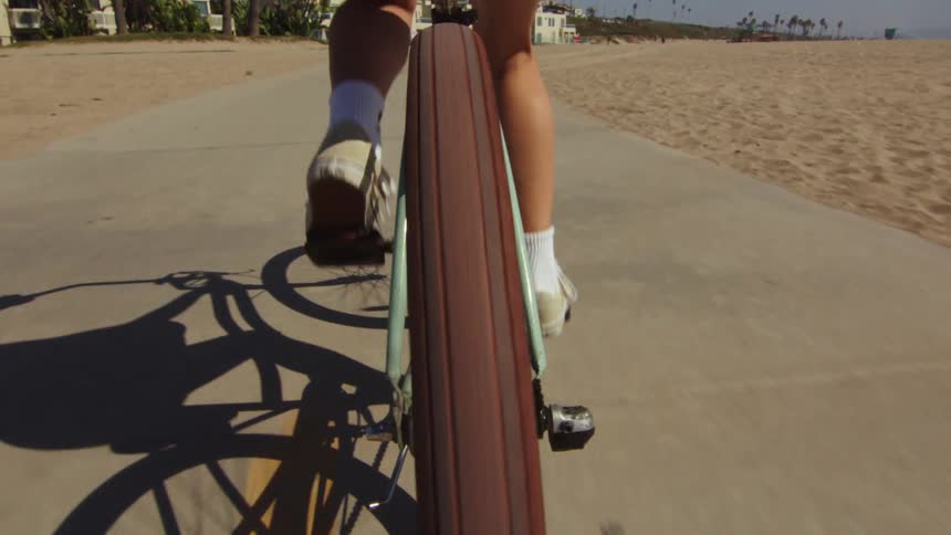 Closeup of a persons legs riding a bicycle on the beachside sidewalk