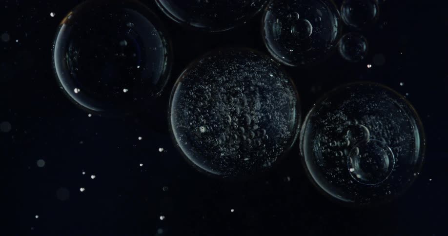 Clear bubbles of various sizes float in spotted blackness